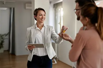 Female Realtor Handing Home Keys to Buyers