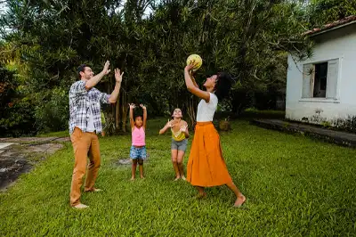 Happy couple with kids playing Ball at gated vacation home Alibaug