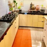 3 BHK Imperial Heights Goregaon West Black Granite Counter Yellow Cabinet Orange Rug U Shape Compact Kitchen