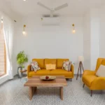 : 4 BHK Villas Elements Nachinola Goa family seating area with yellow sofas wooden coffee table tiled flooring