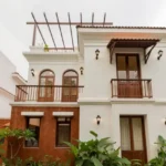 4 BHK Villas Elements Nachinola Goa front elevation with balconies rooftop pergola white exterior facade and landscaped greenery around villa