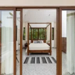 4 BHK Villas Elements Nachinola Goa master bedroom entrance view with wooden bed sliding glass doors striped rug