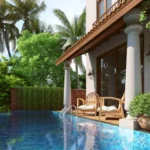 4 BHK Villas Elements Nachinola Goa private poolside seating area with wooden chairs infinity edge swimming pool tropical plants and covered sit out space