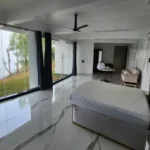 7 BHK Villa Panchgani Mahabaleshwar Interior Bedroom With Bed Large Glass Walls Garden View Marble Flooring And Ceiling Fan