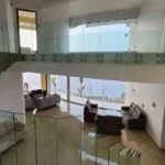 7 BHK Villa Panchgani Mahabaleshwar Interior Double Height Living Area With Mezzanine Glass Railing Sofa Seating And Large Glass Walls