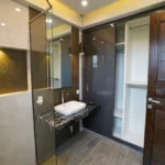Dosti 604 Wagle Estate Thane 3 BHK Designer Bathroom With Vanity Mirror Premium Wash Basin Wooden Door Modern Tile Finish And Contemporary Lighting
