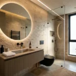 Isle Of Calm Powai 2 BHK modern bathroom with round illuminated mirror, floating vanity and glass shower partition