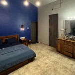 R Paradise Tungarli Lonavala 6 BHK Villa Bedroom With Blue Accent Wall And Wooden Furniture