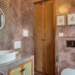 Villa Casa Brilhante Parra Goa 4 BHK Bathroom With Textured Wall Finish Wooden Vanity Decorative Mirror Premium Wash Basin And Contemporary Interior Design