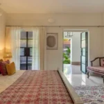 Villa Casa Brilhante Parra Goa 4 BHK Bedroom With Upholstered Bed Vintage Seating Area Large Balcony Doors Soft Curtains