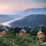 Kiran Canary Forest Plots Aamby Valley Pastel Sky Forested Slope Cabin Row Aerial View