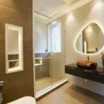 2 BHK The Altimus Khar West Stylish Washroom With Organic Shaped Backlit Mirror Bronze Vessel Sink And Glass Shower