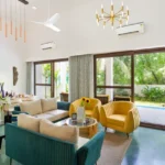 3 BHK Mayberry Villas Anjuna Goa Bright Lounge With High Vaulted Ceiling Yellow Chair And Dining Setup Behind