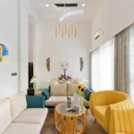 : 3 BHK Mayberry Villas Anjuna Goa Bright Lounge With High Vaulted Ceiling Yellow Chair And Dining Setup Behind