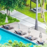 Veda Monteza Plots for Sale Alibaug Swimming Pool with Sun Loungers and Palm Trees